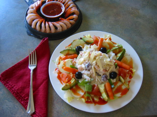 Seafood salad with lettuce, avacados, cucumbers, carrots, onions, grapes and olives, topped with swiss cheese